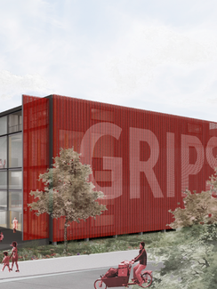GRIPS in einem XXL-Container mit roten Außenwänden und großem GRIPS Schriftzug. Der Container ruht auf Säulen, so dass kein vollständiges Fundament benötigt wird, was CO2 spart und Versickerung begünstigt. Das Gebäude ist in 3 Bereiche unterteilt, vorne ein mehrstöckiges Foyer mit Spielmöglichkeiten (Rutsche, Netzboden), in der Mitte die 2 Bühnen übereinander, nach hinten die Funktionsbereiche.